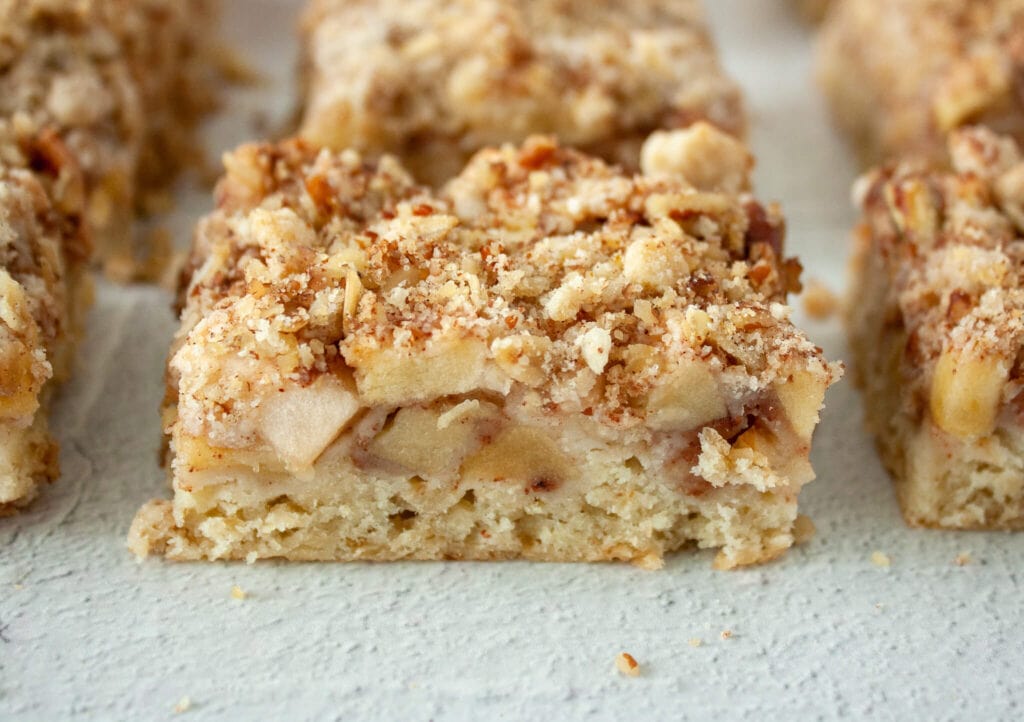 Close up photo of an apple bar that highlights the cinnamon apple and apple crisp layers. 