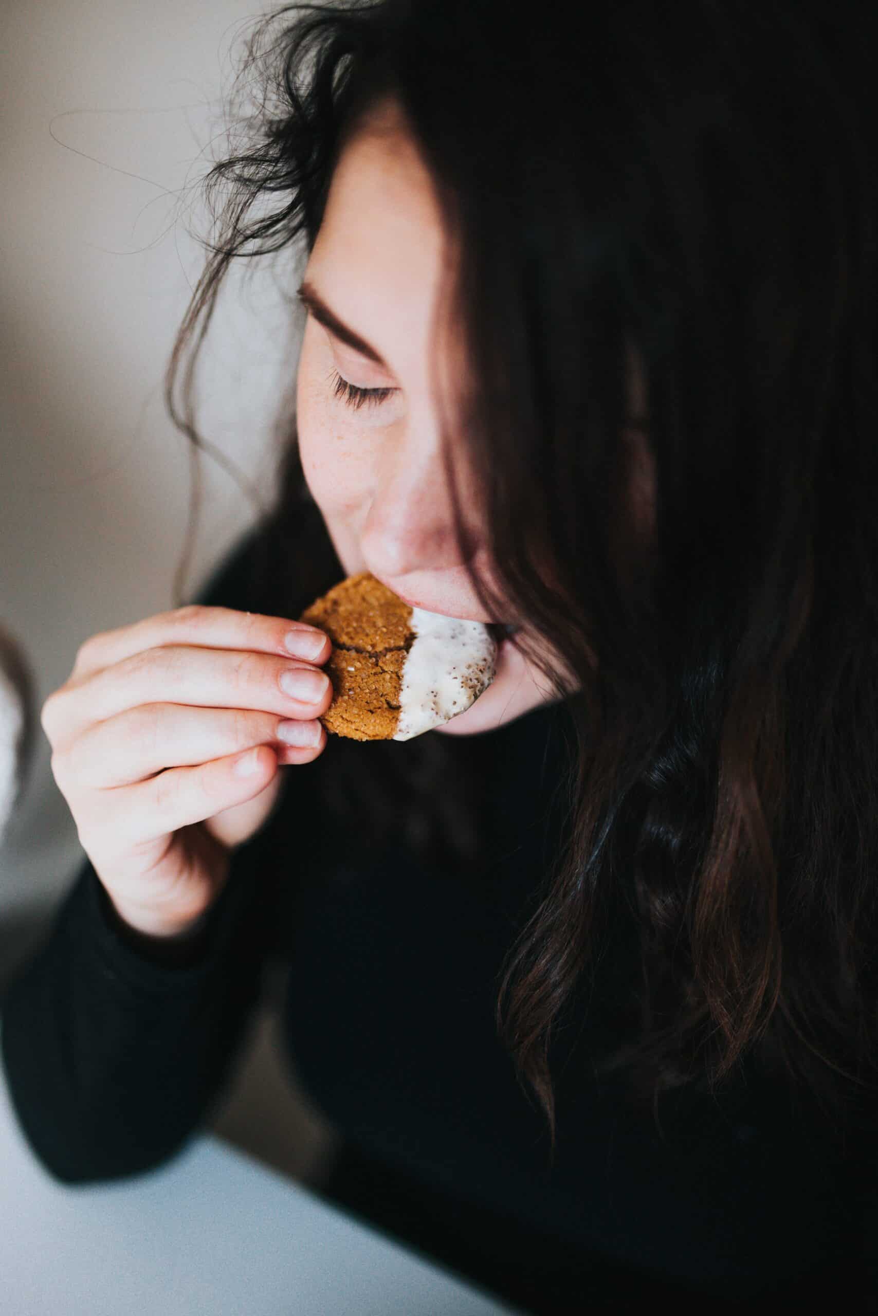 Decorative website photo of a women with dark hair eating a cookie